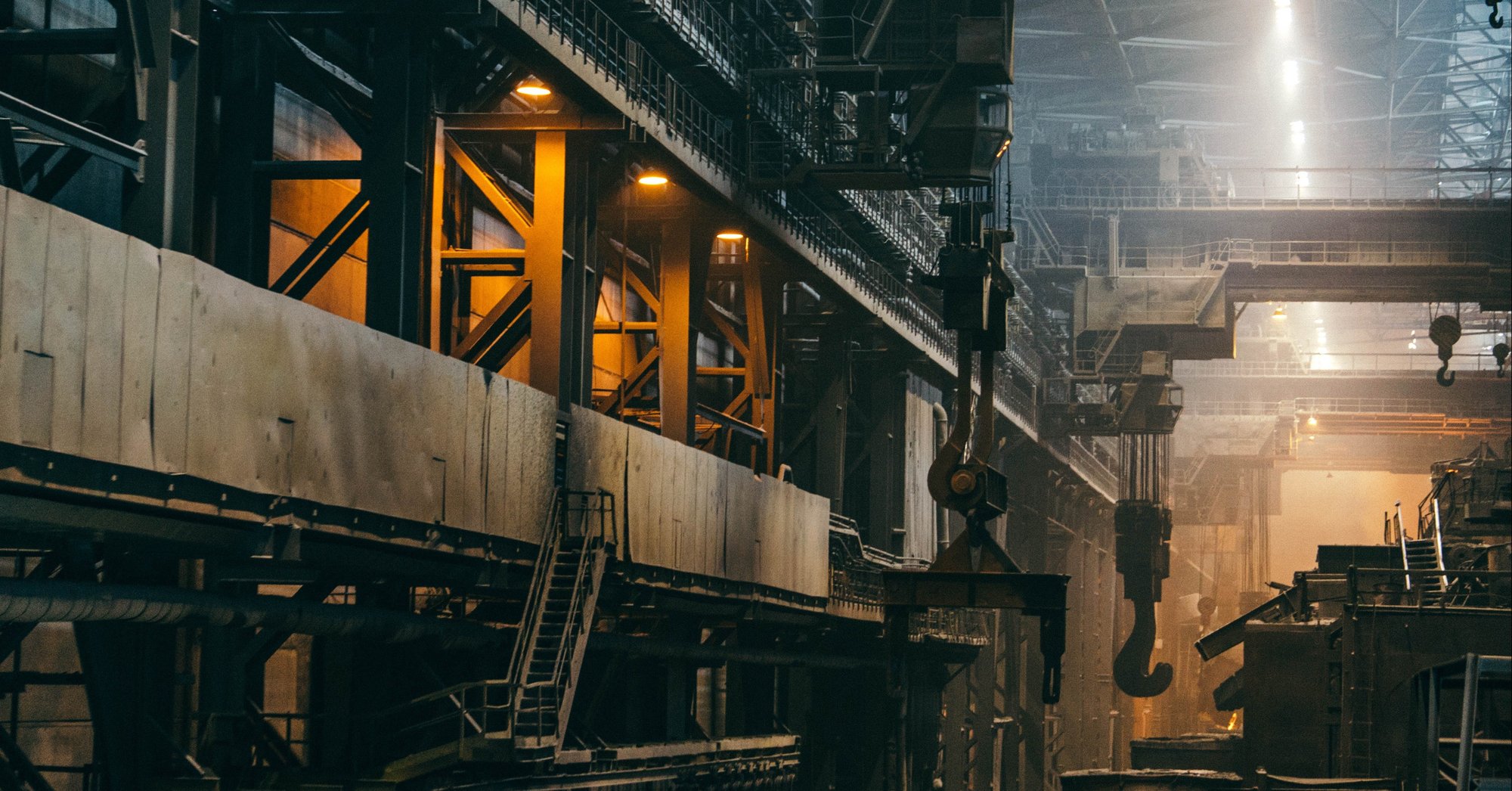 empty interior of a warehouse, with cranes sitting unoccupied 