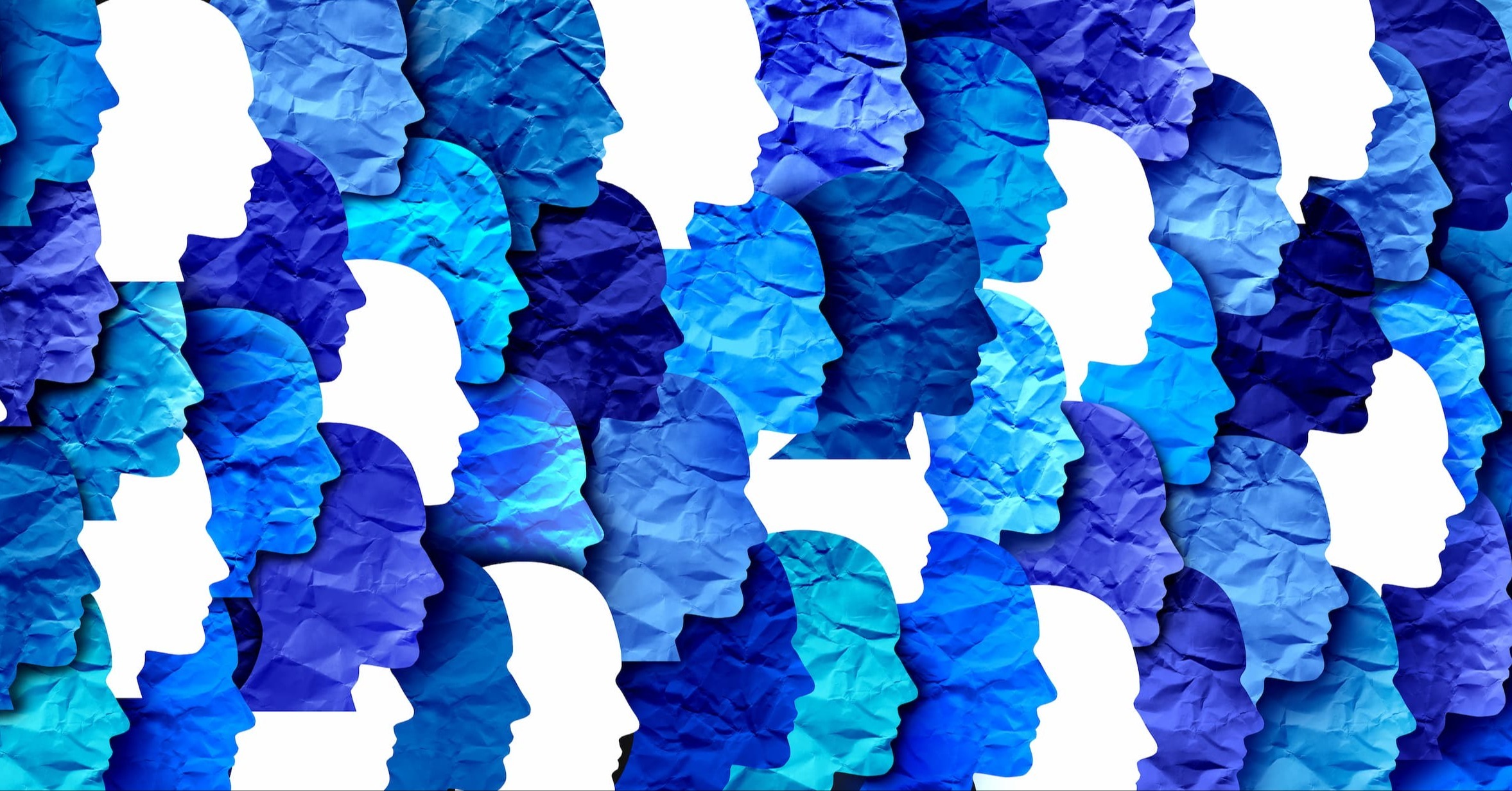 Abstract pattern of overlapping human profile silhouettes in layered shades of blue, resembling textured paper cutouts.