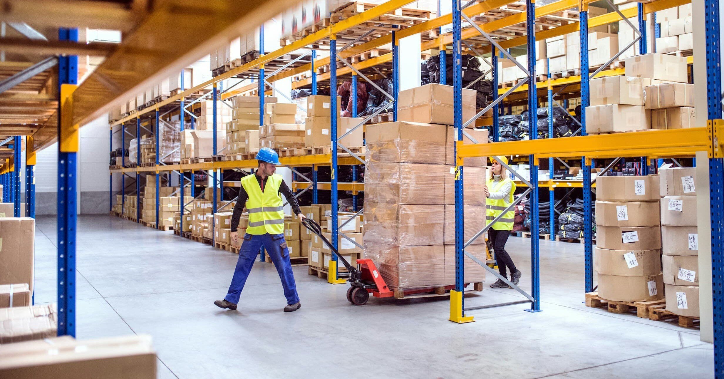 two workers transporting packages inside a warehouse